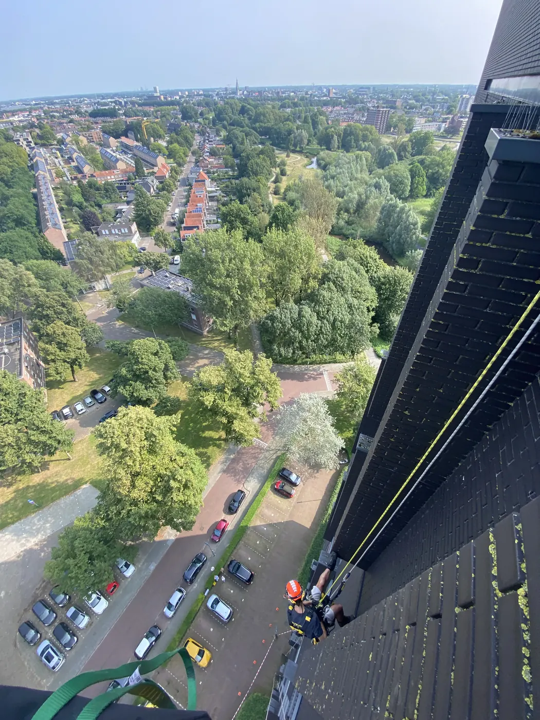 Bovenaanzicht van een klimmer langs een hoge flatgevel