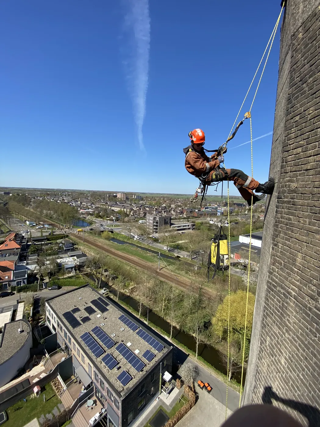 Abseilende klimmer met materiaaltas langs een watertoren